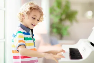 Lapsi soittaa iloisena pianoa.