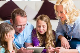 Kaksi aikuista ja kaksi lasta katselevat ipadia tai tablettia